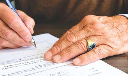 a man signing a piece of paper in close-up.